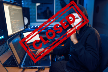 Masked hacker at a computer with his finger to his lips.  A red closed stamp across the picture